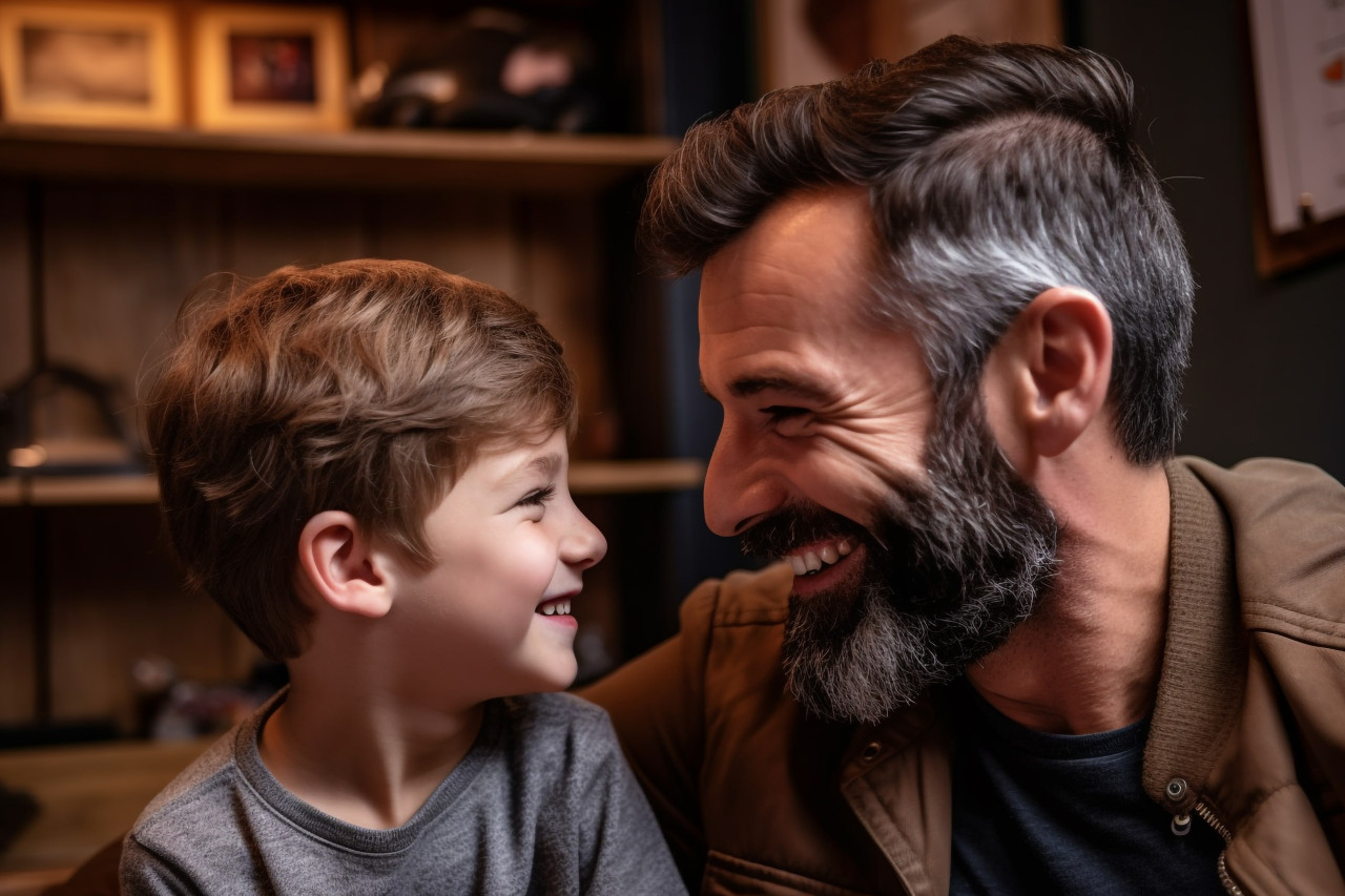 A picture of a handsome dad and his sweet son facing each other and smiling enjoying time at home, indoor activities for kids