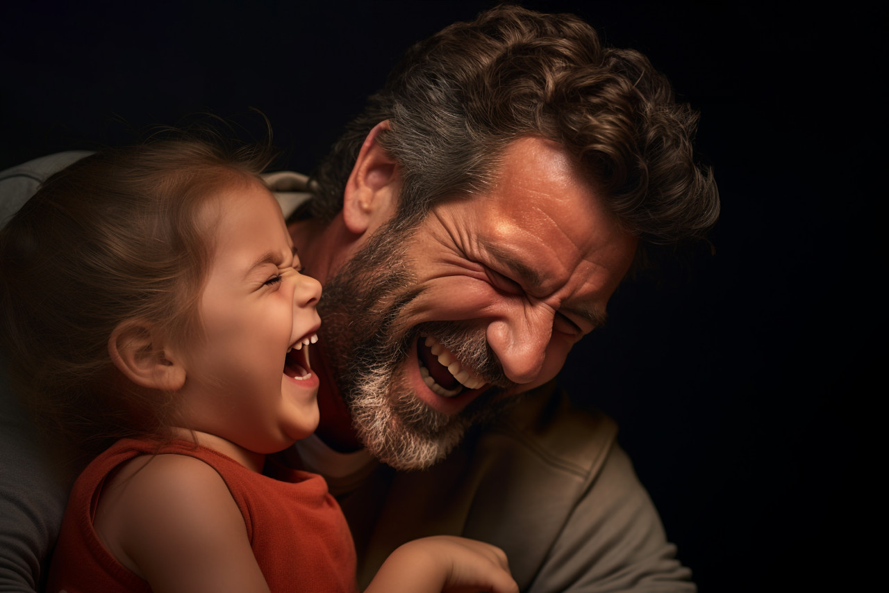 A picture of a dad making his little girl laugh by tickling her, lifestyle children indoors activitie