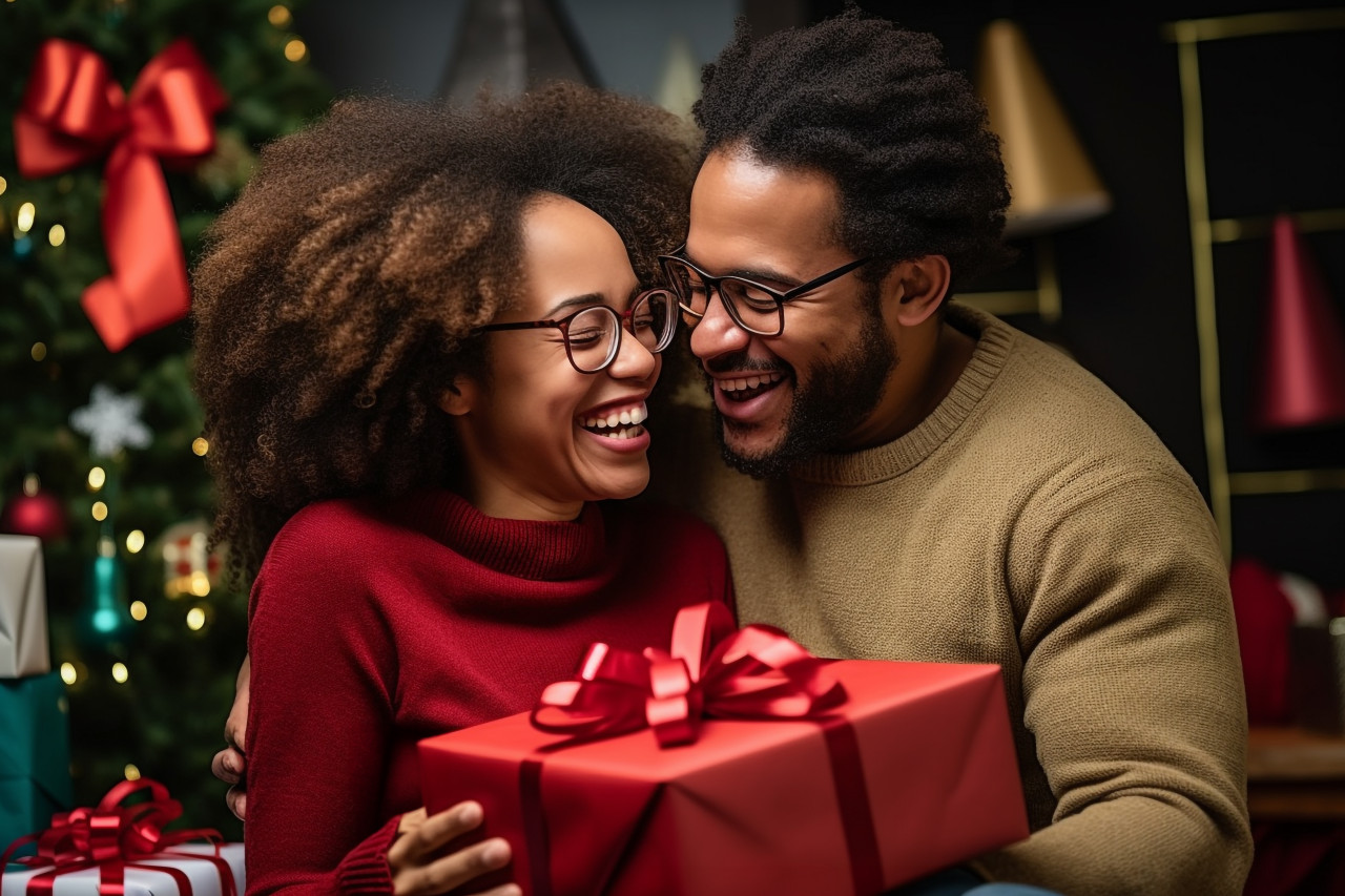 A photo of a very happy african american couple hugging and exchanging christmas presents at home during the winter holidays, christmas festival people image