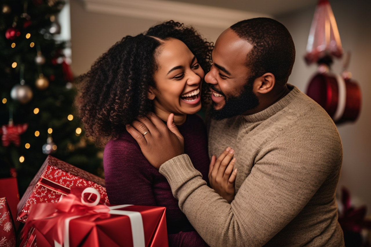 A photo of a very happy african american couple hugging and exchanging christmas presents at home during the winter holidays