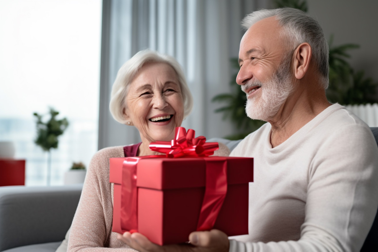 Picture of a happy old woman with a gift box sitting next to a man in a hotel room, festivals and occasions anniversary image