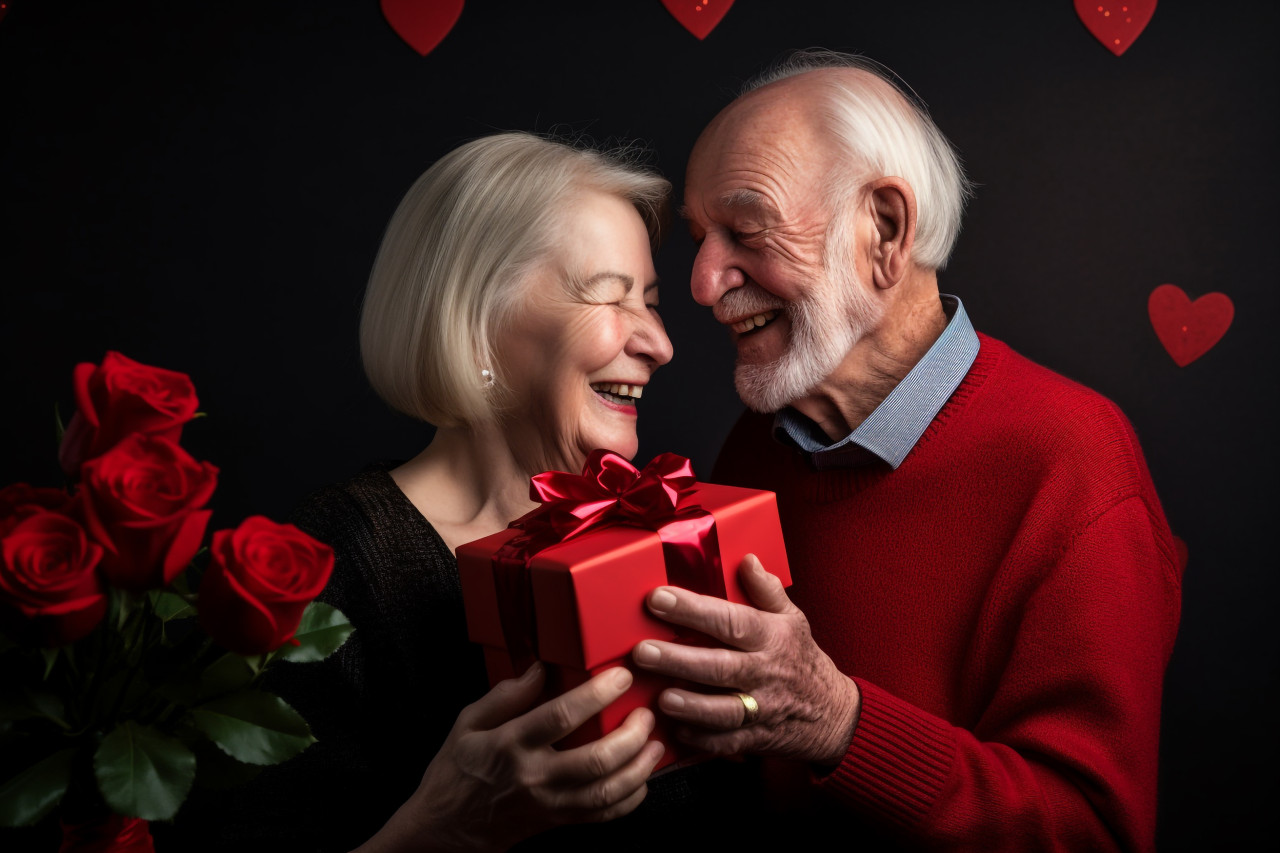 A photo of an old couple celebrating their anniversary with a gift. they are smiling happily and excitedly, festivals and occasions anniversary image