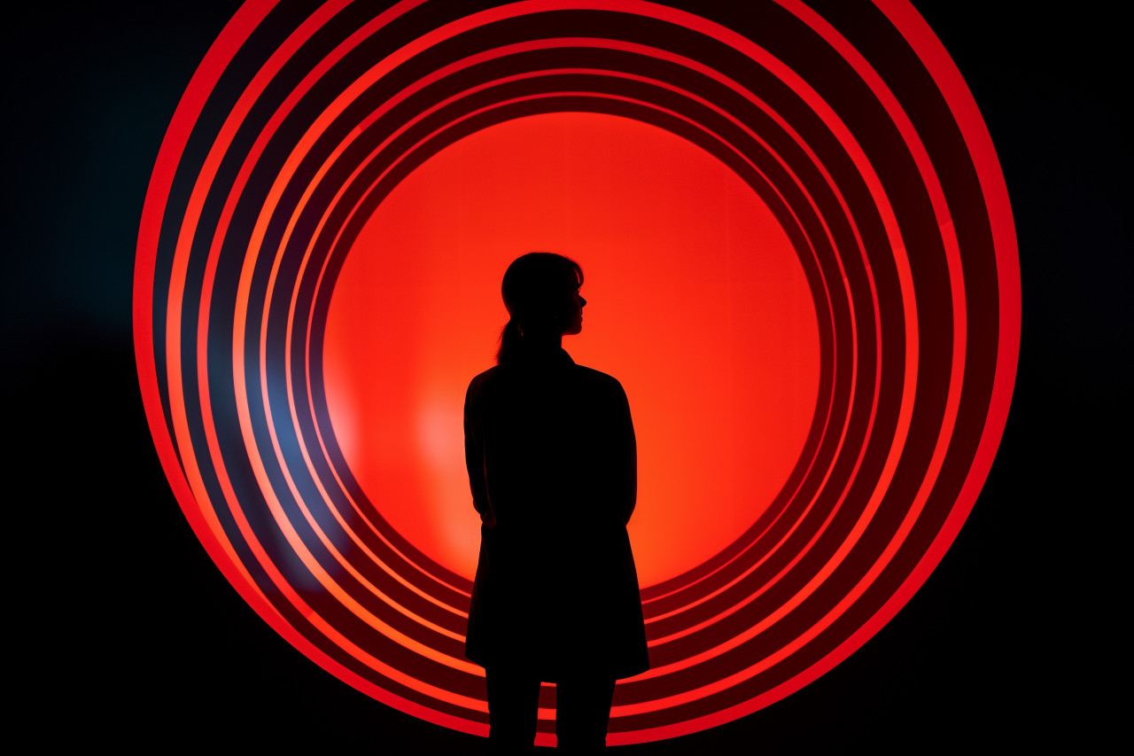 A woman outline can be seen against a round bright hole, futuristic image