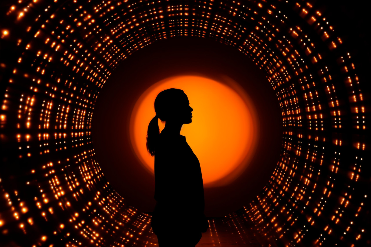 A woman outline can be seen against a round bright hole, futuristic image