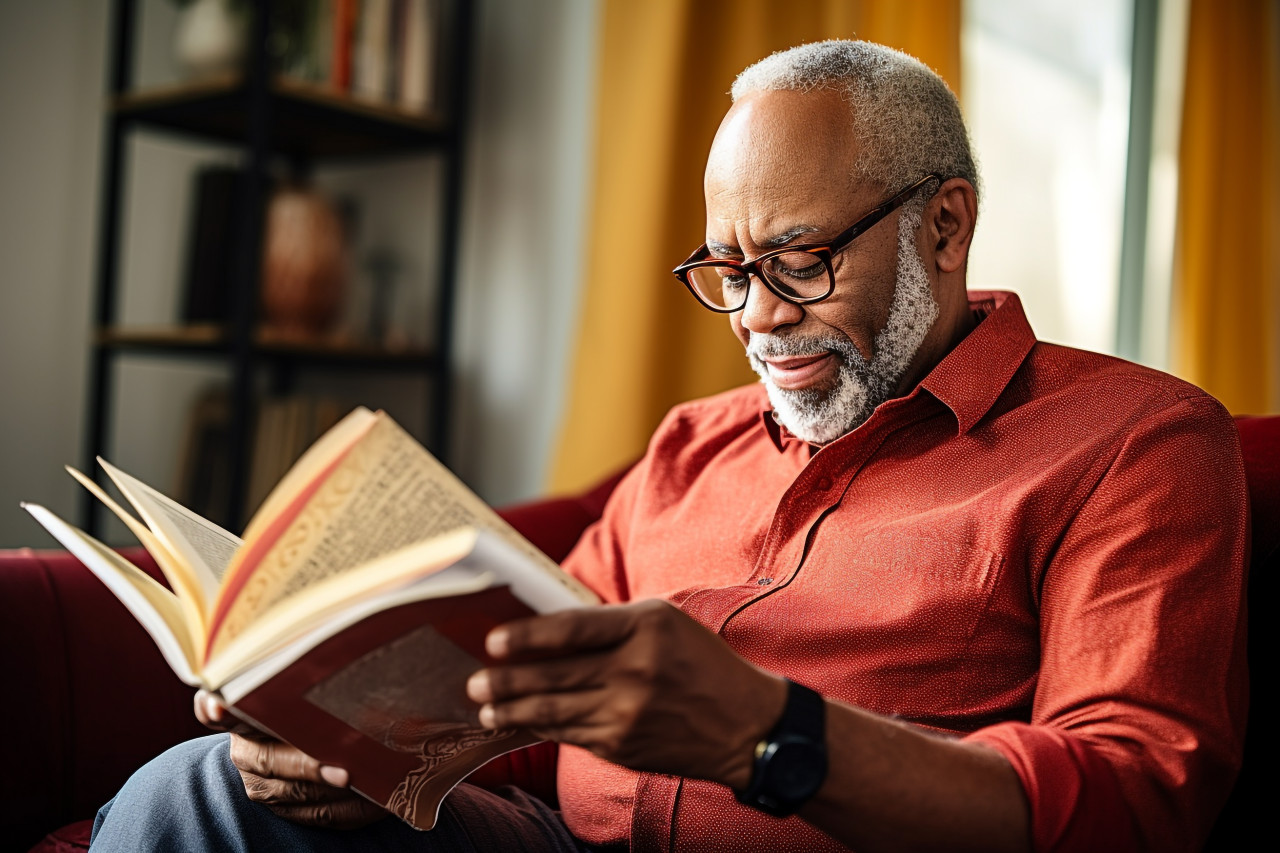 Smiling african american man reading book at home