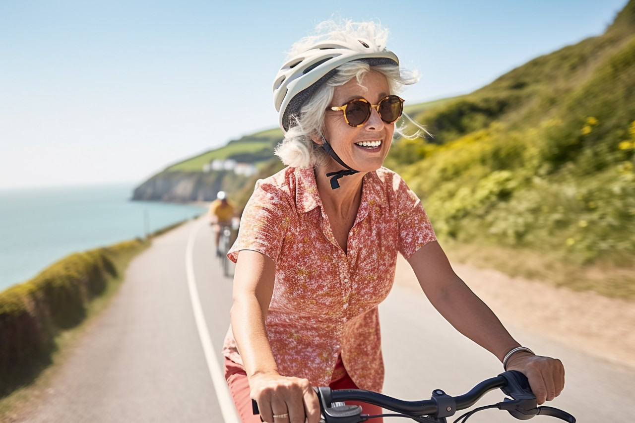 Cheerful woman cycling on scenic coastal trail