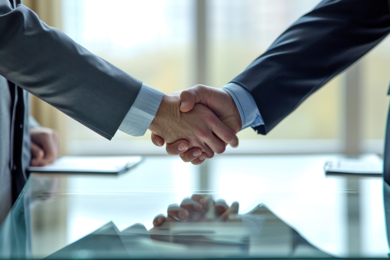 Businessmen shake hands over a table after reaching a successful deal, business meeting photo
