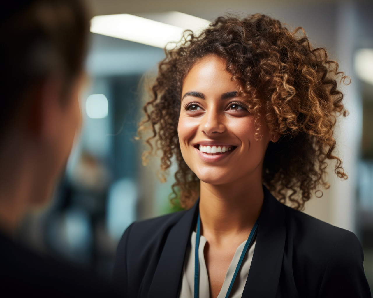 A young businesswoman chatting to colleague in office discussing work with a smile, hiring image for job postings