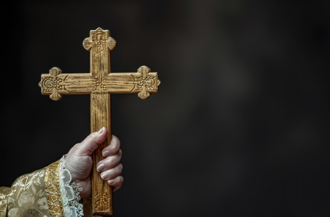 A female hand holding wooden cross, palm crosses concept