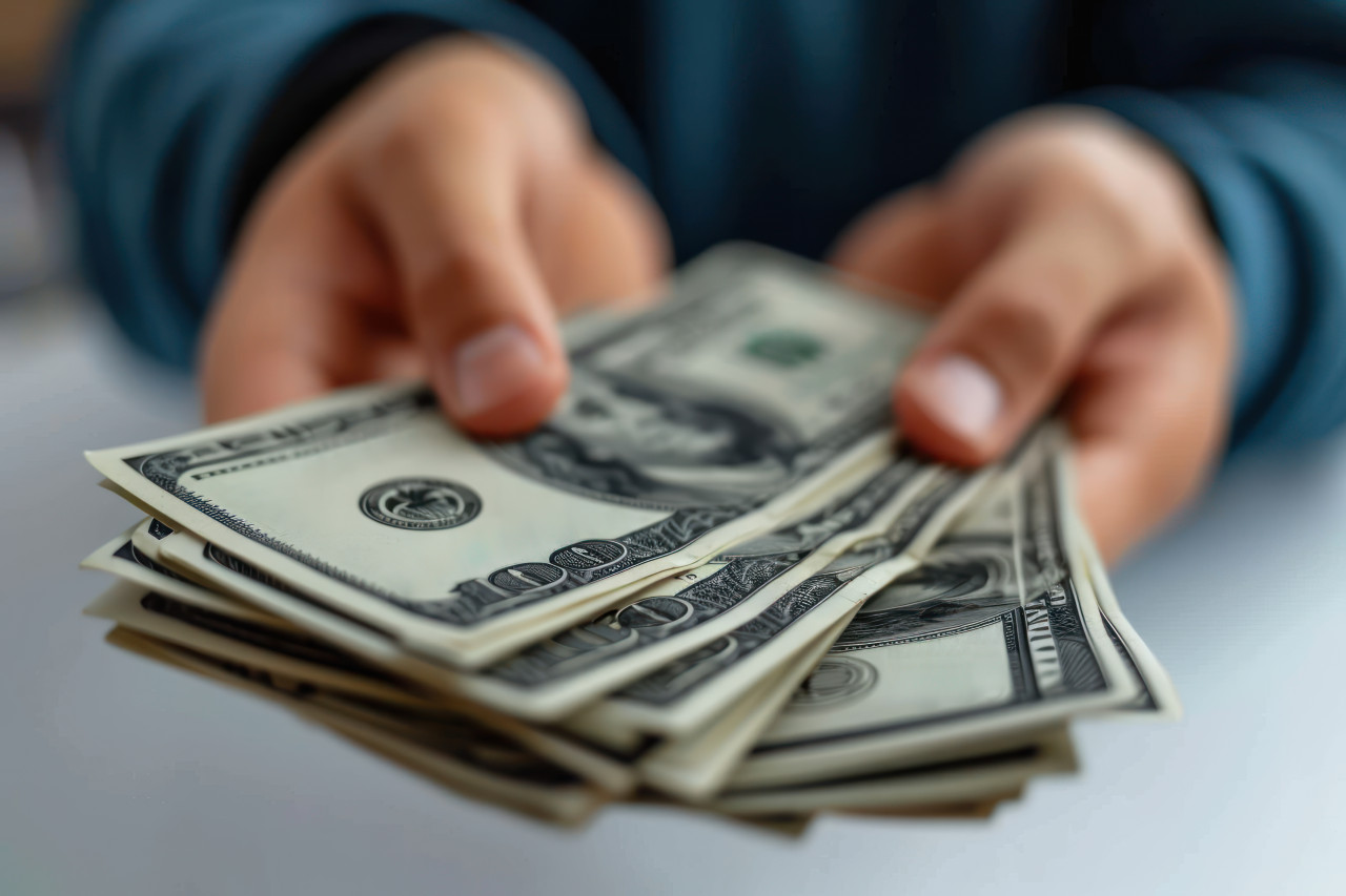 Male hand counts us dollars in a close up emphasizing financial success and business concept, debt acceptance concept