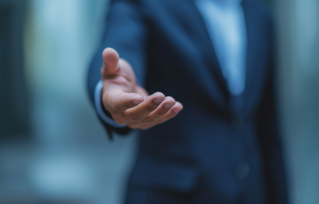 A professional showcases an open palm symbolizing trustworthiness and sincerity in business interactions, brand launch concept