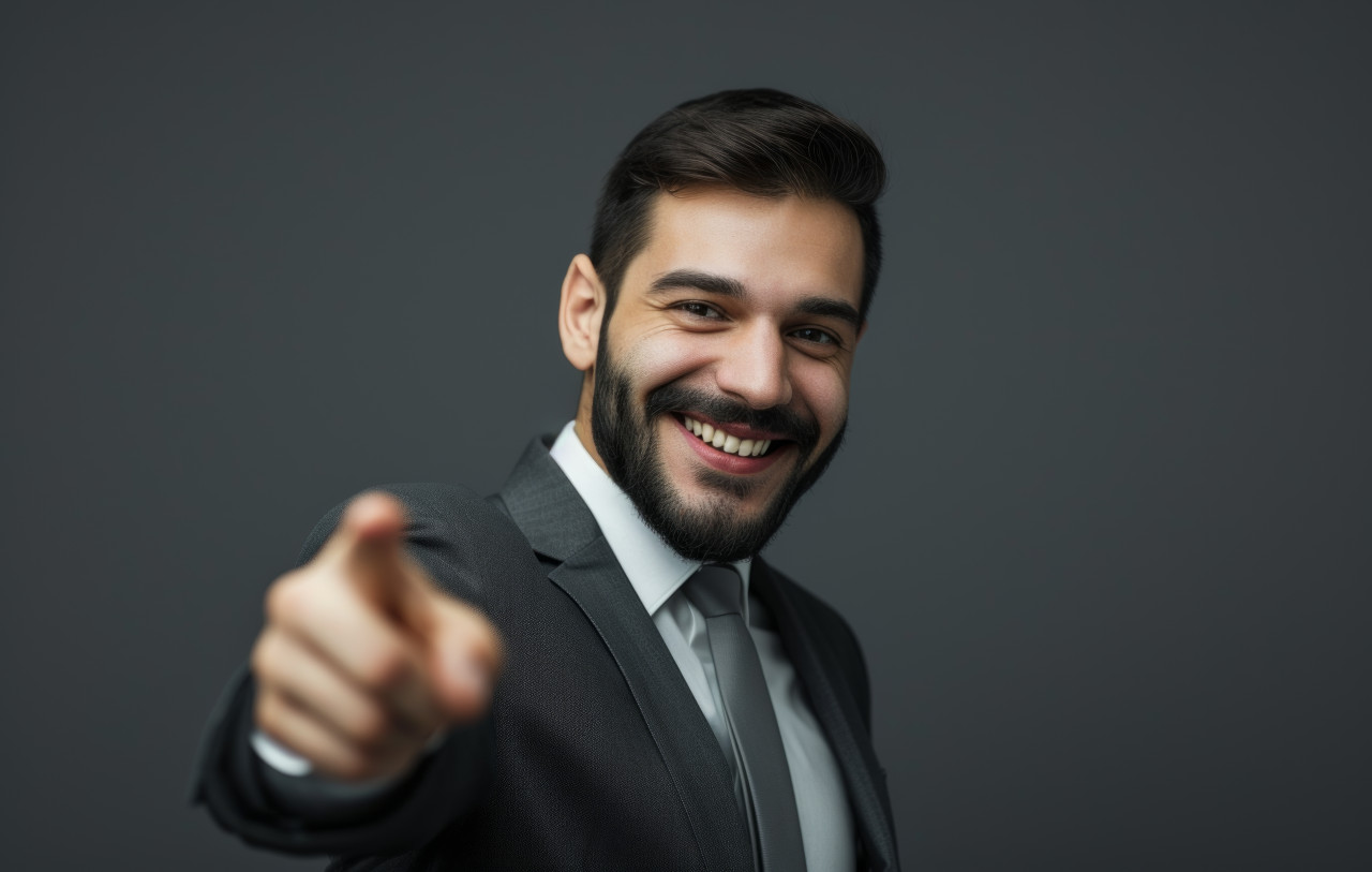 Happy businessman pointing finger at camera with a smile, brand launch concept