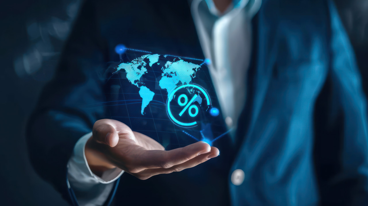 Businessman holding digital virtual world map and percent icon demonstrating global business and finance concept