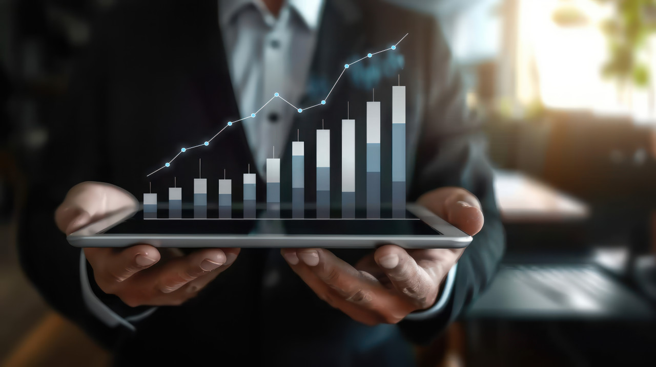 Businessman holding tablet displaying rising graph chart analyzing sales performance, digital business analysis, sales trends