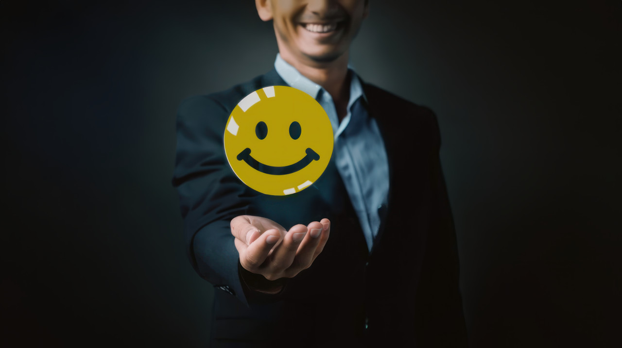 Businessman holding yellow smiley face icon illustrating feedback concept, customer satisfaction, positive feedback