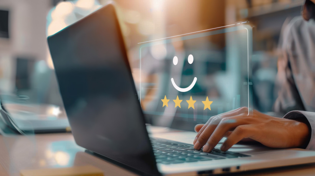 Person using laptop with virtual smiley face and four star icons showing customer satisfaction and positive feedback, happy client experience, user review