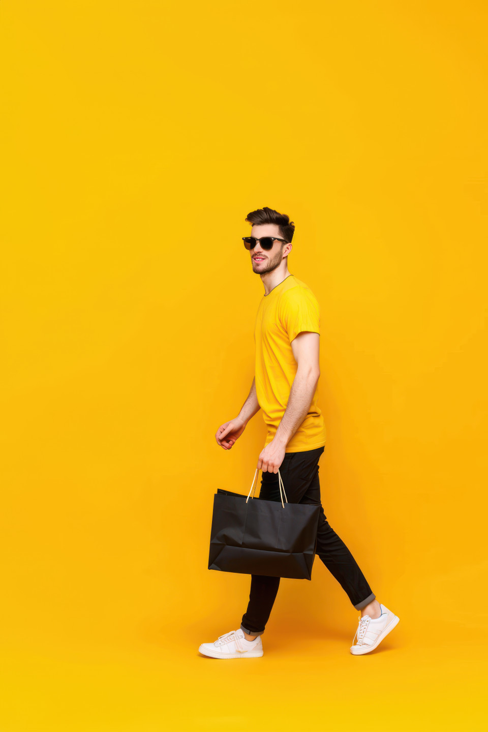 A man in sunglasses and a yellow t shirt carrying a black shopping bag representing black friday sales, black friday, shopping fashion