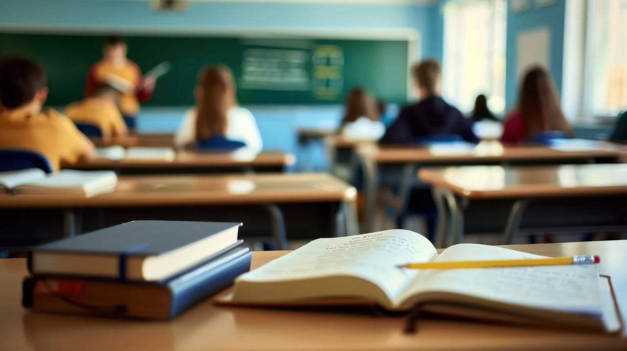 Empty classroom with students at desks in the background and books on one desk
