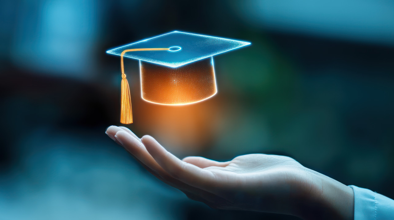 Hand holding graduation cap icon floating above it representing educational technology