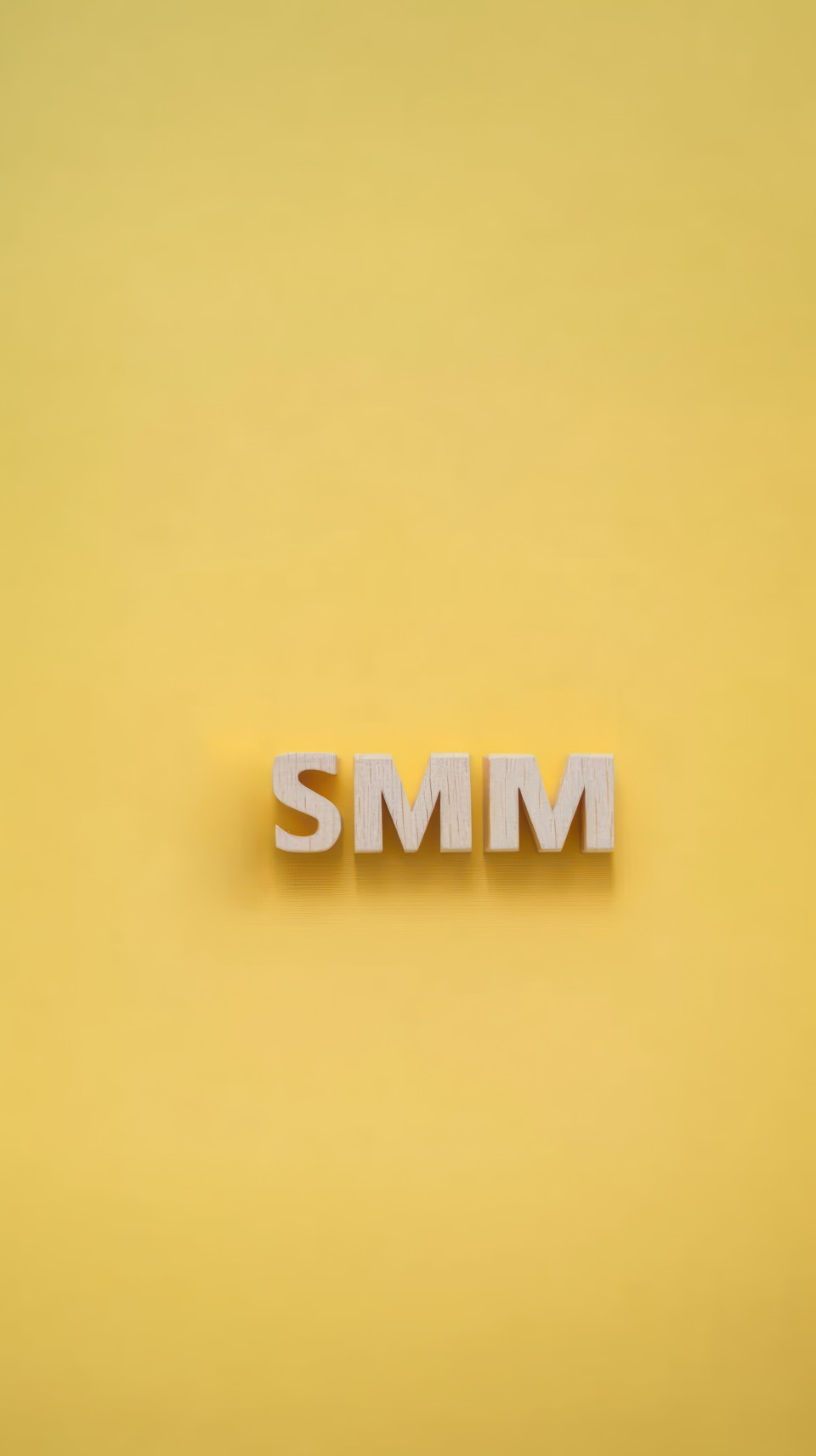 Smm letters made of wooden blocks on a light yellow background, illustrating the basic building blocks of social media marketing, digital strategy, smm tools, marketing foundation