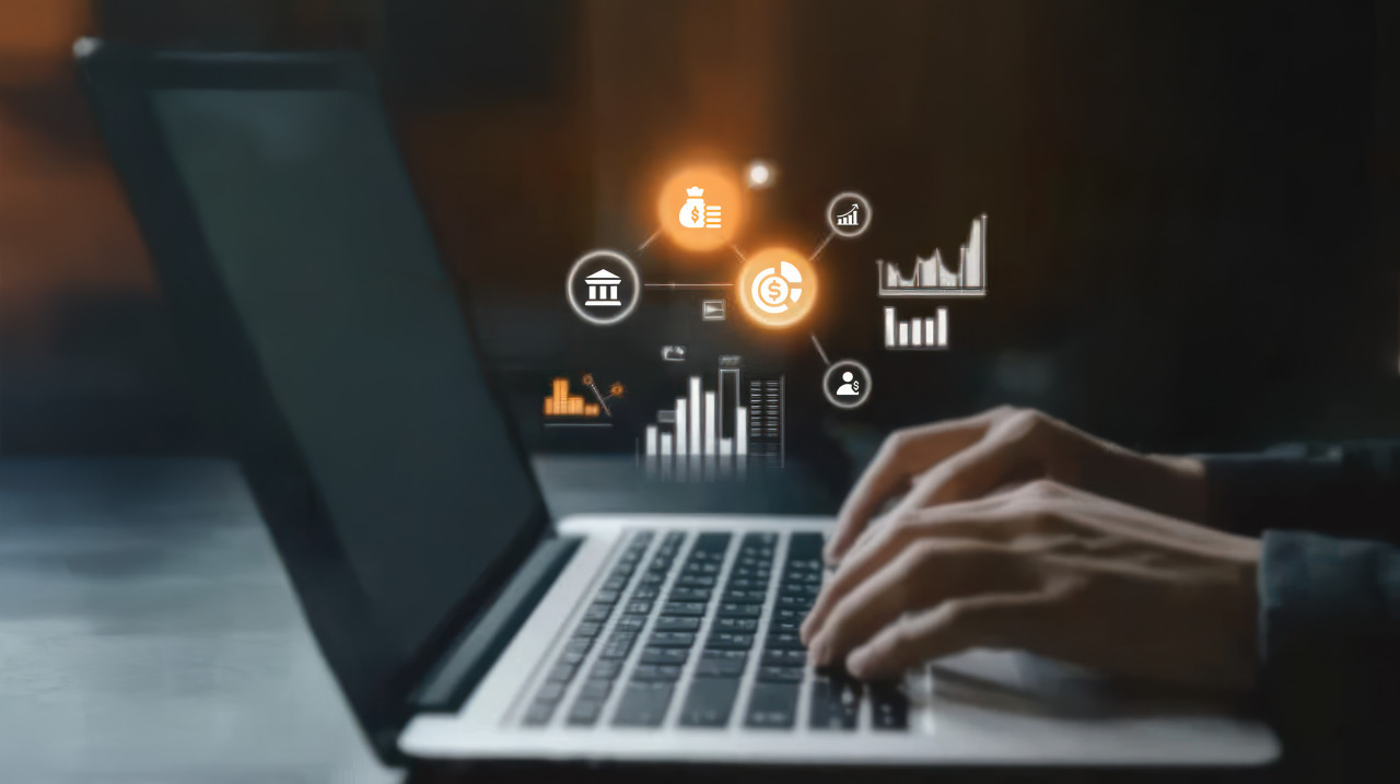 Person using laptop to create floating business growth icons and graphs, financial literacy, financial coaching, money management