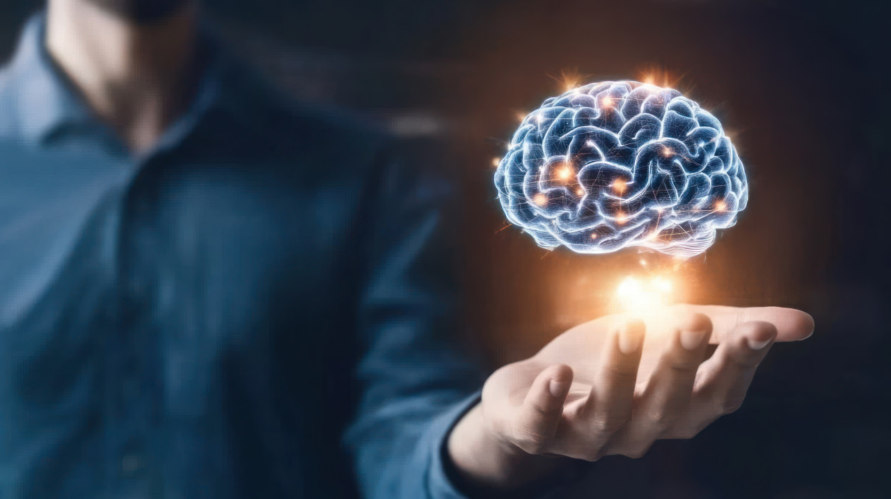 A hand holding a glowing brain hologram against a digital tech background, symbolizing ms awareness, neural innovation, and multiple sclerosis concepts