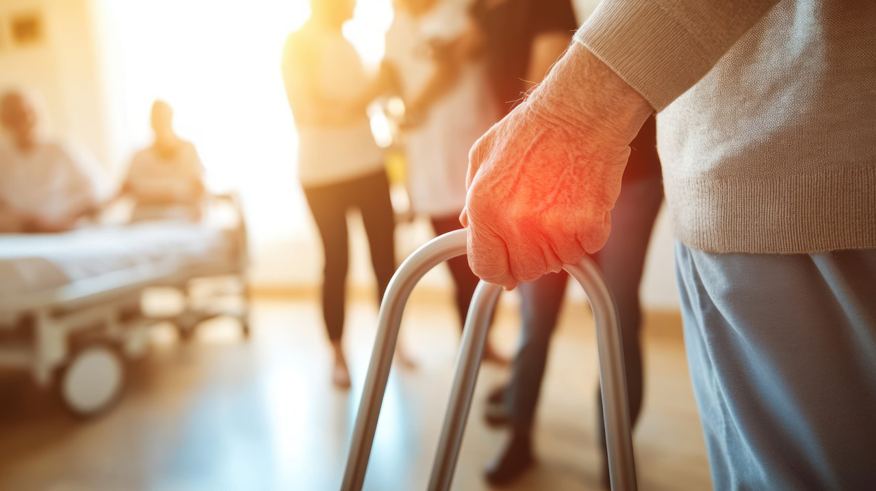 Close up of hands holding crutches as an elderly man uses a walker in his living room, geriatric pt focuses on improving mobility through geriatric physiotherapy