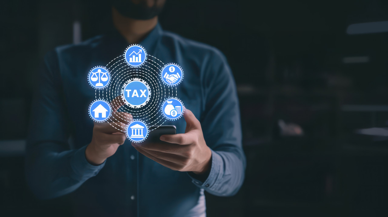 A person holds a phone displaying tax and financial icons, the image highlights tax services, digital tools, and financial planning