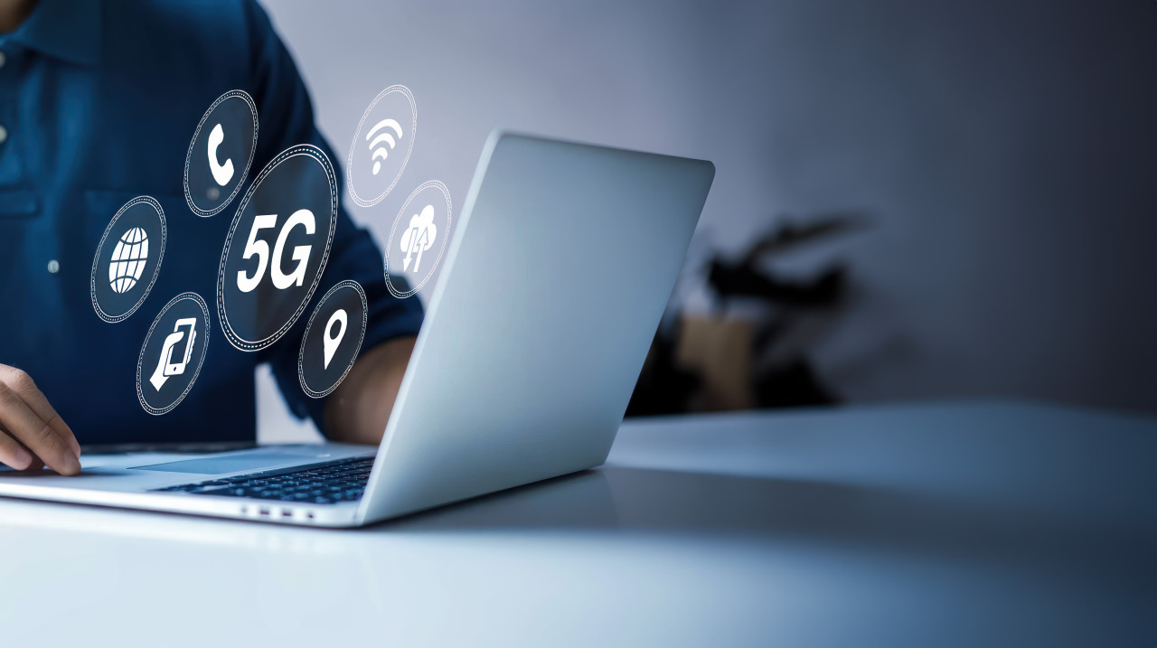 A man hand using a laptop with a 5g icon on the screen, showing internet connectivity, data transfer, 5g activation, and 5g expansion