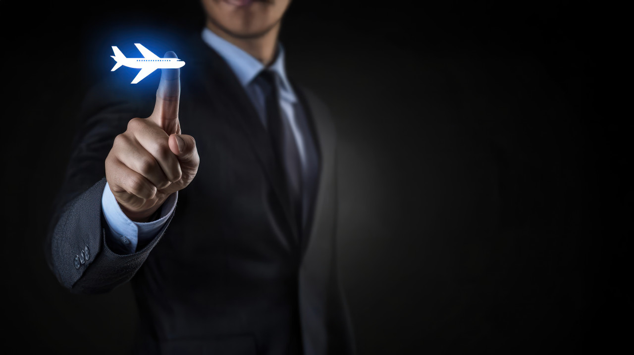 Businessman touching airplane icon on virtual screen over black background, highlights travel disruptions and cancelled flights