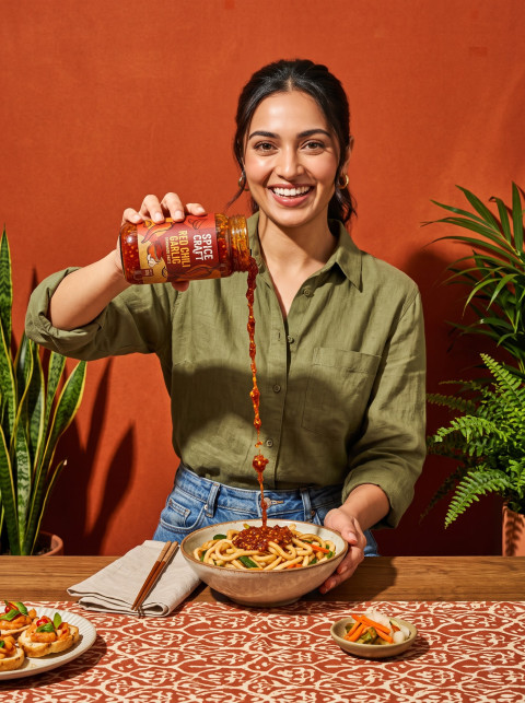 Smiling Woman Pouring Chili Paste Over Noodles